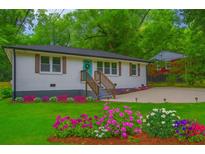 Charming home with a well-maintained lawn and vibrant flower beds, complemented by a turquoise front door at 831 Catherine St, Forest Park, GA 30297