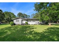 Charming single-story home with a lush green lawn and mature trees, providing a welcoming curb appeal at 205 Tamea Trl, Covington, GA 30014