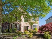 Inviting brick home featuring a meticulously landscaped front yard with lush greenery and mature trees at 630 Bluff Oak Ct, Roswell, GA 30076