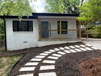 Charming home with a white painted brick, covered front porch and a stone walkway through the landscaped front yard at 875 Hall Nw St, Atlanta, GA 30318