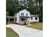 Charming white home with a convenient drive-through carport and a well-manicured lawn and driveway at 169 Long Dr, Marietta, GA 30060