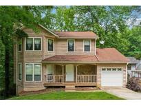 Charming two-story home with a cozy front porch and attached garage, nestled among lush greenery at 706 Cather Ct, Stone Mountain, GA 30088