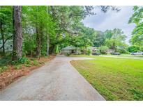 Charming single-story home featuring a long driveway and a lush, green front yard with mature trees at 1774 Austin Dr, Decatur, GA 30032