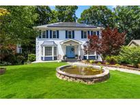 Charming two-story home with a well-manicured lawn, blue accents, and a decorative front pond at 4909 Glenwhite Dr, Duluth, GA 30096