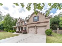 Two-story brick home with two car garage, manicured lawn and lovely, mature trees at 882 Nestling Dr, Lawrenceville, GA 30045