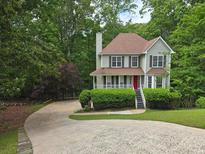 Charming two-story home boasts a red front door and lush landscaping, nestled among mature trees at 1511 Harbor Watch Ct, Woodstock, GA 30189