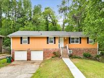 Charming home featuring brick accents, a two-car garage, and a welcoming entrance in a lush, green setting at 1563 Greenwood Dr, Norcross, GA 30093