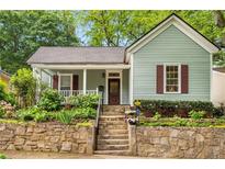 Charming home featuring stone retaining wall, inviting front porch, and meticulous landscaping at 865 Ashland Ne Ave, Atlanta, GA 30307