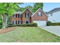 Charming two-story brick home featuring a well-manicured lawn and inviting curb appeal at 5574 Wynhall Dr, Peachtree Corners, GA 30071