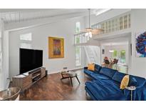 Bright living room featuring vaulted ceilings, modern decor, hardwood floors, and cozy blue sofa at 495 Ramsdale Dr, Roswell, GA 30075