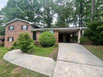 Two-story brick home featuring a covered carport and mature landscaping at 1263 Shoreham Dr, Atlanta, GA 30349