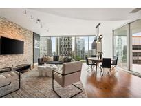 Inviting living room with a decorative stone wall, hardwood floors, and a stunning city view through expansive windows at 20 10Th Nw St # 2003, Atlanta, GA 30309