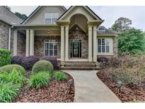 Inviting brick home entrance with a covered porch and landscaped walkway at 5195 Stefan Ridge Way, Buford, GA 30519