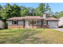 Charming single story home featuring brick accents, a well-manicured lawn, and inviting curb appeal at 6801 Red Maple Dr, Rex, GA 30273