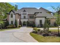 Elegant brick and stucco home featuring a circular driveway and manicured landscaping at 140 Johnson Rd, Suwanee, GA 30024