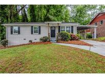 Charming single-story home with painted brick, black shutters, a cozy front porch, and lush landscaping at 2796 Green Trail Dr, Atlanta, GA 30349