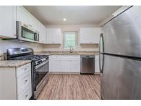 Updated kitchen featuring stainless steel appliances, granite countertops, and wood-look flooring at 3497 Glensford Dr, Decatur, GA 30032