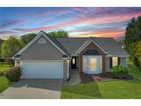 Charming single-story home showcasing a landscaped front yard, bay window, and two-car garage with a beautiful sunset in the background at 2602 Midler Ct, Buford, GA 30519