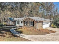 A well-maintained brick home featuring a two-car garage and manicured landscaping at 574 Oak Grove Rd, Temple, GA 30179