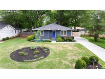 Charming single story home with landscaped front yard, featuring a blue front door and a long driveway at 957 Sharon Se Cir, Smyrna, GA 30080