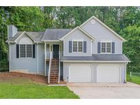 Charming home features a two-car garage and inviting front stairs, complemented by lush green landscaping at 2326 Westland Way, Acworth, GA 30102