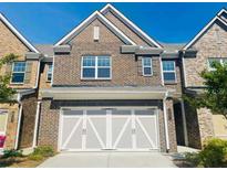 Charming brick townhome with a two-car garage and well-maintained landscaping at 1216 Foxcroft Ln, Cumming, GA 30041