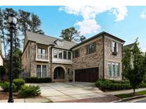 Charming brick home showcasing lush landscaping, large garage, and a well-maintained front yard at 1811 Kent Ave, Dunwoody, GA 30338