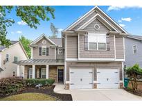 Charming two-story home with a two-car garage, landscaped front yard, and inviting covered porch at 449 Highlands Loop, Woodstock, GA 30188
