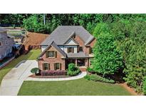 Charming brick home featuring a well-manicured lawn, mature trees, and a long driveway at 1168 Woodtrace Ln, Auburn, GA 30011