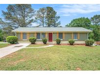 Charming one-story home with a well-manicured lawn, shutters and a welcoming red front door at 898 Doeskin Nw Dr, Conyers, GA 30012