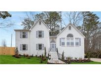 Charming white brick two-story home featuring blue shutters, complemented by a well-maintained front yard and professional landscaping at 101 Saddlehorn Ct, Woodstock, GA 30188