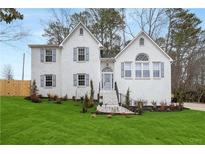 Charming two-story home featuring a white brick exterior, well-manicured lawn, and elegant front entrance at 101 Saddlehorn Ct, Woodstock, GA 30188