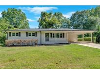 Charming single-story home with a well-manicured lawn and a covered parking area, offering a blend of comfort and style at 3951 Lindley Dr, Powder Springs, GA 30127