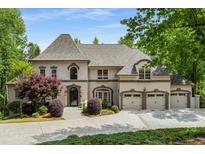 Stately home featuring manicured landscaping, stone driveway, and a three-car garage, exuding curb appeal at 8345 Jett Ferry Rd, Sandy Springs, GA 30350