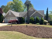 Charming home featuring manicured front lawn, mature landscaping, and an attached two-car garage at 2435 Jakin Way, Suwanee, GA 30024