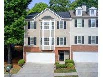Charming townhome featuring a brick facade, black shutters, and attached two-car garage at 376 Eagle Tiff Dr, Sugar Hill, GA 30518