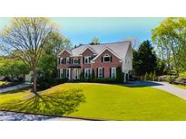 Classic brick home featuring manicured lawn, long driveway, and symmetrical design at 4015 Dodds Grove Ln, Alpharetta, GA 30009