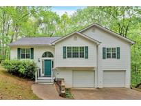 Charming two-story home with white siding, green shutters, and a two-car garage nestled amongst lush trees at 2539 Lakeside Dr, Villa Rica, GA 30180