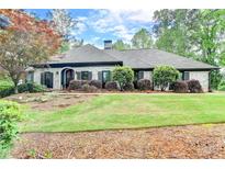 Beautiful one-story home with a manicured lawn and mature trees, showcasing its curb appeal at 5475 Trowbridge Dr, Dunwoody, GA 30338