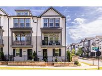 Charming townhome with a gray and white facade, a small balcony, and a well-manicured lawn at 834 S Columbia Dr, Decatur, GA 30030