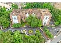 An aerial view of a brick apartment building surrounded by lush greenery and ample parking at 2965 Pharr Court South Nw # 718, Atlanta, GA 30305