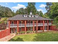 Sprawling brick home featuring a double porch, manicured lawn, and mature trees for an inviting curb appeal at 7180 Westray Rd, Cumming, GA 30028
