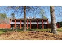 Expansive brick home featuring a wide porch, white railing, and large columns at 7180 Westray Rd, Cumming, GA 30028