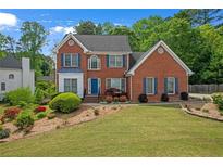 Charming red brick two-story home with manicured lawn and blue shutters and a blue front door at 1665 Little Lisa Ln, Snellville, GA 30078