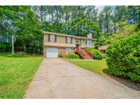 Charming split-level home with a brick facade, a wooden staircase, and an attached garage at 2132 Sara Ashley Way, Lithonia, GA 30058