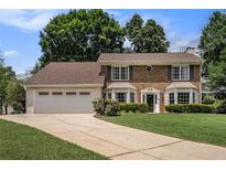 Charming brick home featuring a two-car garage, manicured lawn, and traditional design elements at 130 Floss Flower Ct, Roswell, GA 30076
