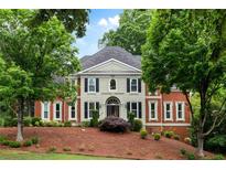 Stately brick home featuring classic architecture, arched entry, dark shutters, and mature landscaping at 790 Thornberry Dr, Alpharetta, GA 30022