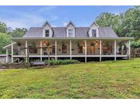 Charming home featuring a sprawling front porch with hanging plants, greenery and a swing at 143 Navajo Trl, Rydal, GA 30171
