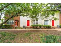 Exterior view of townhomes featuring colorful doors, tidy landscaping, and a lush green space in front at 238 Chads Ford Way, Roswell, GA 30076