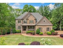 Beautiful two-story brick home featuring a well-manicured lawn, mature trees, and a welcoming front porch at 106 Stephens Farm Dr, Canton, GA 30115